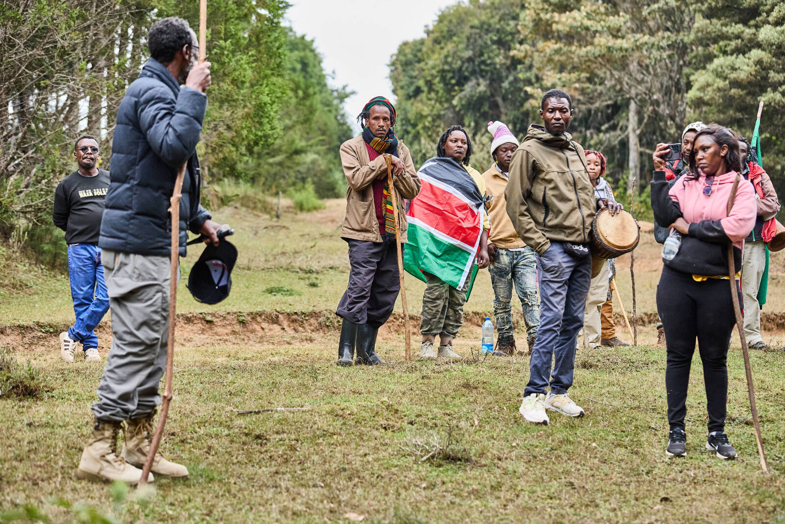 Community members gathered with staffs and a Kenyan flag during a heritage walk