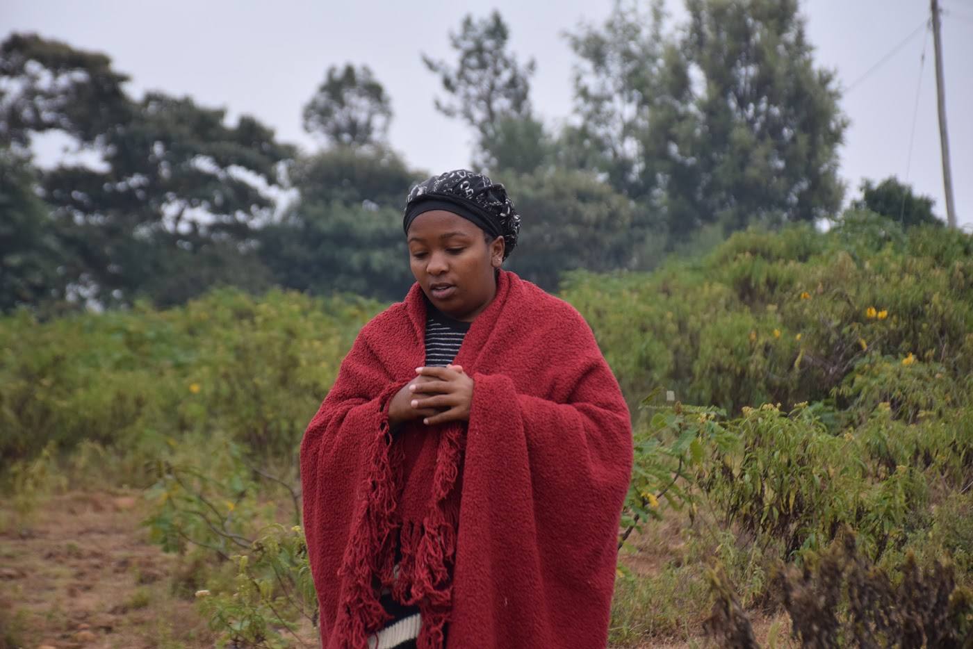 A woman wrapped in a red shuka standing on the dry slope